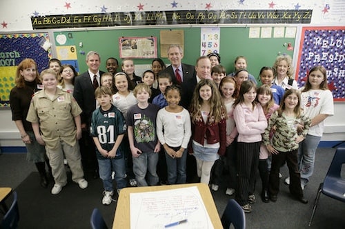 President George Bush, a class of Indiana elementary school students, their two teachers, the governor of Indiana, and an Indiana congressman stand together for a group portrait in the children’s classroom.
Photographer: Eric Draper. Source: George W. Bush White House Archives. https://georgewbush-whitehouse.archives.gov/news/releases/2007/03/images/20070302-8_d-0236-5-515h.html. 2 Mar 2007. Public domain via Wikimedia Commons.
